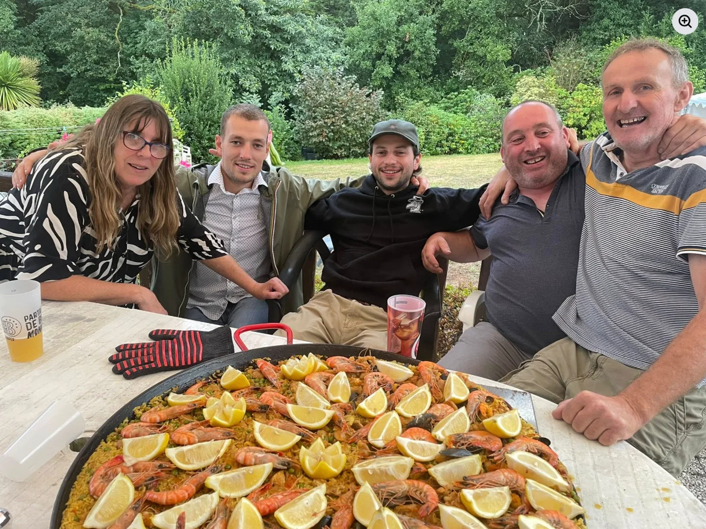 Laurence et ses clients autour d'une grande paella maison en extérieur